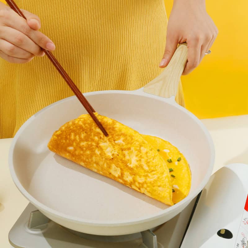 Fluffy omelette cooking in a non-stick pan with a yellow background, showcasing breakfast preparation at Monalisa Medical Store.