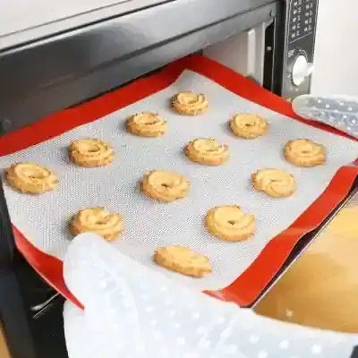 Freshly baked cookies coming out of a commercial oven with a silicone baking mat.
