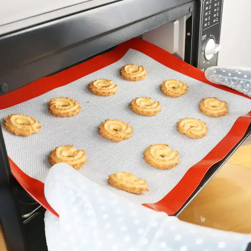 Freshly baked cookies coming out of a commercial oven with a silicone baking mat.