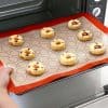 Delicious homemade fruit cookies baking on a silicone mat in front of an oven, perfect for a cozy baking session or family treat.