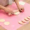 Cutting dough with a rolling pin on a pink silicone baking mat for baking or pastry making at Monalisa Store.