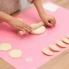Cutting dough with a rolling pin on a pink silicone baking mat for baking or pastry making at Monalisa Store.
