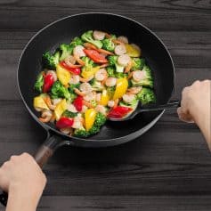 Fresh shrimp and colorful bell peppers stir-fried in a black wok for a healthy meal, emphasizing fresh ingredients and vibrant dish presentation.