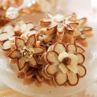 Delicious flower-shaped cookies decorated with white chocolate and chocolate drizzle, perfect for holiday treats or gift-giving. Elegant and festive dessert from Monalisa Medical Store.