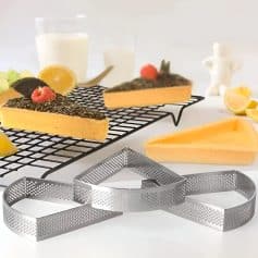 Deluxe cheesecake slices on cooling rack with lemon wedges and fresh raspberries, next to Monalisa Store baking tools, ideal for luxury dessert presentation and professional pastry making.