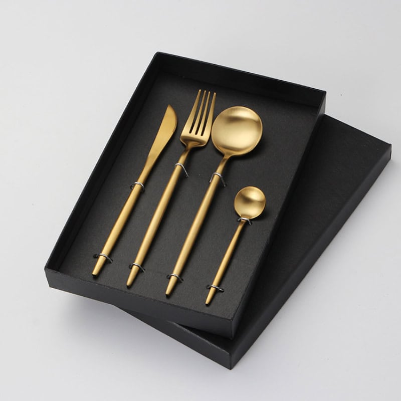 Elegant gold cutlery set including knife, fork, spoon, and teaspoon in stylish black presentation box, perfect for upscale dining and kitchen decor.