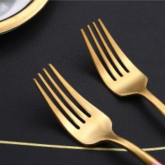 Shiny gold forks on black textured background, elegant tableware set, sophisticated dining utensils, Monalisa Medical store product display, stylish cutlery for fine dining.