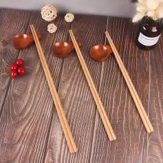 Elegant wooden chopsticks, matching spoons, and decorative accents on a stylish wooden dining table, ideal for enhancing your dining experience at Monalisa Store.