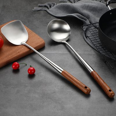 Stainless steel and wooden handle ice cream scoops on a modern kitchen countertop, with fresh cherries, cookware, and a cutting board, showcasing high-quality kitchen tools from Monalisa Store.