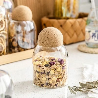 Organic herbal mixture storage jar with cork lid for wellness products.