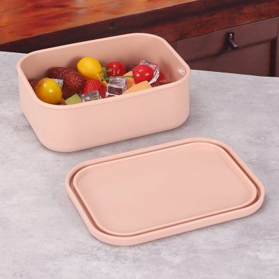 Fresh fruit and ice cubes stored in a pink plastic container, ideal for healthy snacks and food storage.