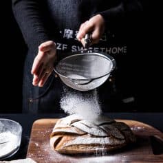Flour sifting over freshly baked bread at Monalisa Store, emphasizing artisanal baked goods and quality ingredients for a delightful bakery experience.