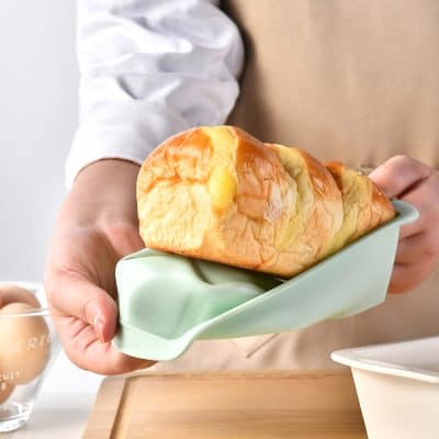 Soft and fluffy bread loaf with a golden crust, placed in a light green dish, showcasing fresh bakery items at Monalisa Store, perfect for breakfast or snacks.