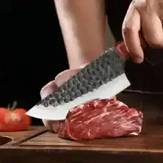 Premium chef's knife slicing fresh raw beef for cooking or preparation, emphasizing high-quality kitchen tools and culinary techniques.