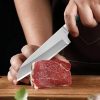 Sleek chef's knife slicing fresh raw beef steak on cutting board for high-quality culinary preparation.