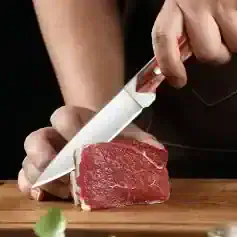 Fresh raw beef steak being sliced with a sharp knife at Monalisa Store for quality meats.