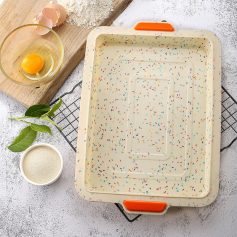 Freshly baked cake baking tray with colorful sprinkles, eggs, flour, and baking ingredients on a textured surface. Perfect for baking enthusiasts and pastry chefs.