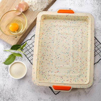 Freshly baked cake baking tray with colorful sprinkles, eggs, flour, and baking ingredients on a textured surface. Perfect for baking enthusiasts and pastry chefs.