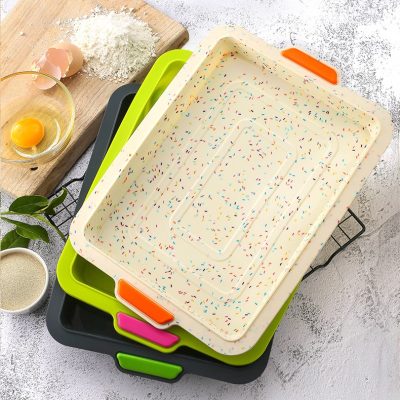 Colorful baking trays stack on a kitchen counter with baking ingredients and eggs around, ideal for preparing delicious desserts and pastries at Monalisa Store.