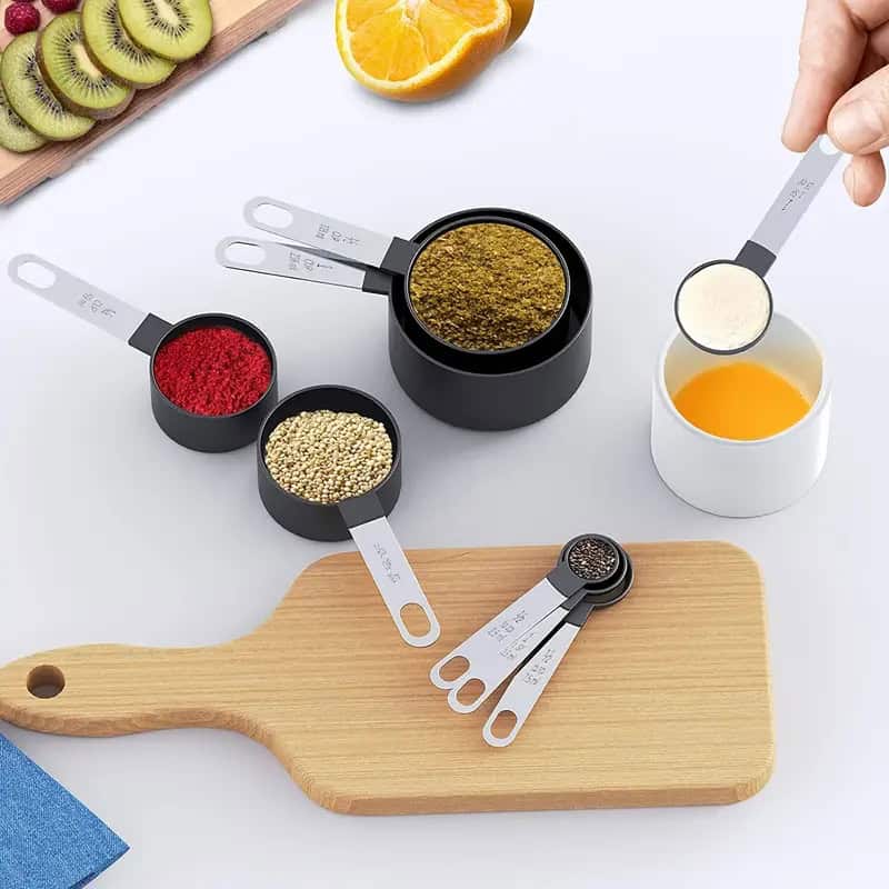 Fresh fruit and spice ingredients including kiwi, orange, and various seasonings arranged on a light background with measuring spoons and a cutting board, emphasizing health and natural products.