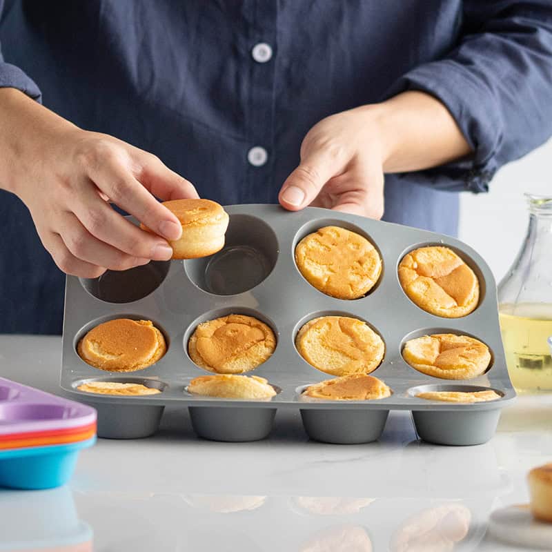 Delicious homemade cupcakes being removed from a baking tray; close-up of baking process, sweet baked treats, cupcake baking, kitchen baking, dessert preparation.