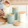 Cream-colored and pastel green storage jars with wooden lids, perfect for kitchen organization and food storage, featured on Monalisa Store.