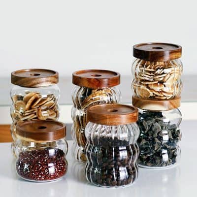 Glass jars with wooden lids filled with various supplements, herbs, and natural remedies for eye health and vision support at Monalisa Store.