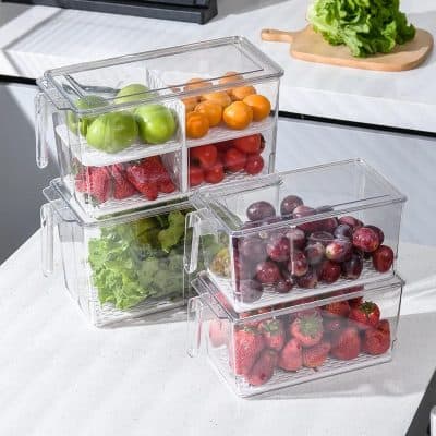 Green and red apples, cherry tomatoes, and strawberries stored in clear plastic containers on a kitchen countertop.