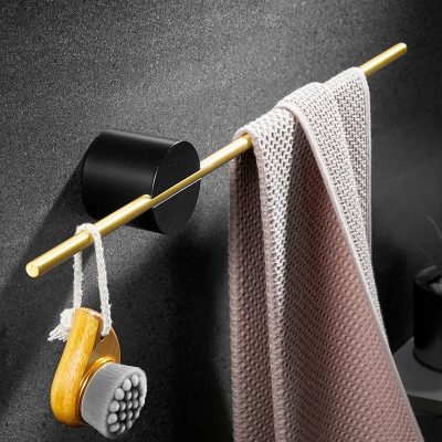Cleaning brush hanging on a gold towel rack with a pink textured towel draped over it in a modern bathroom setting.