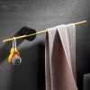 Soft towel hanging on a gold rod in a modern bathroom with toiletries and black wall backdrop for skincare and beauty care essentials.