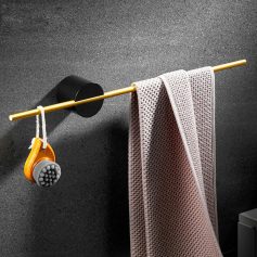 Soft towel hanging on a gold rod in a modern bathroom with toiletries and black wall backdrop for skincare and beauty care essentials.