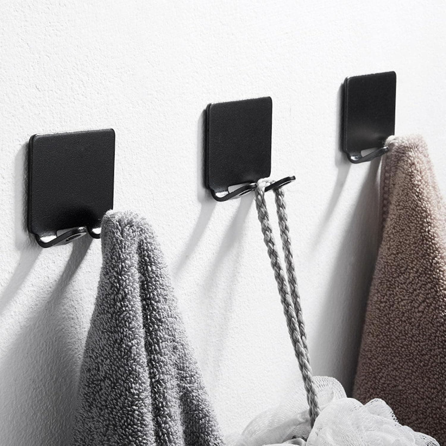 Soft gray and beige towels hanging on black wall hooks at Monalisa Medical Store, showcasing organized towel storage solutions for a clean and professional healthcare environment.