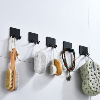Silicone and natural stone bath accessories hanging on black hooks in a modern bathroom setting.