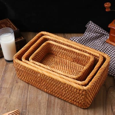 Wicker baskets stack on a wooden table with a glass of milk, checkered cloth, and vintage items; perfect for storage and organization.