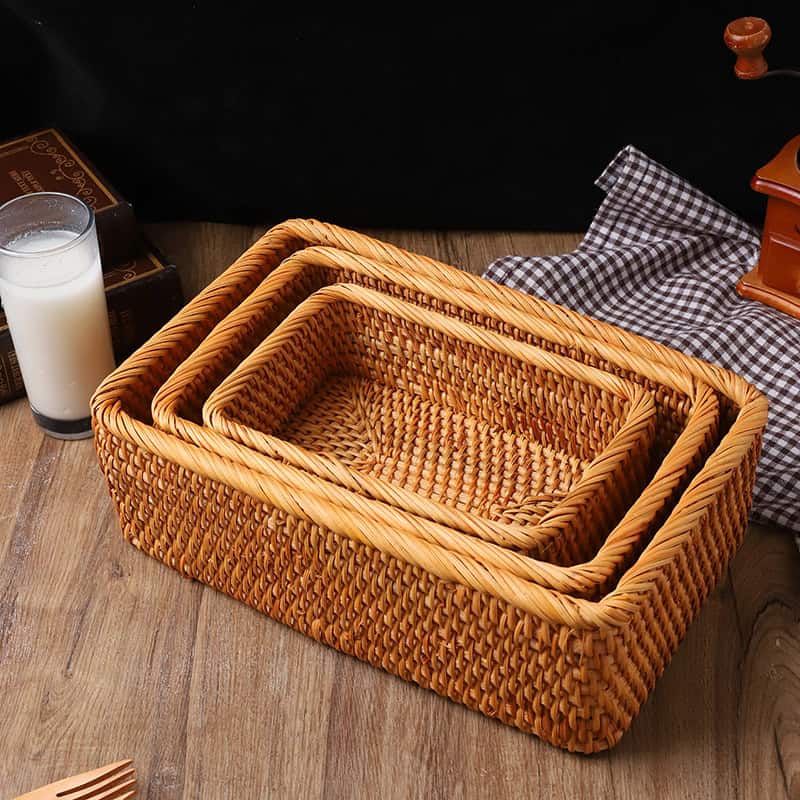 Wicker baskets stack on a wooden table with a glass of milk, checkered cloth, and vintage items; perfect for storage and organization.