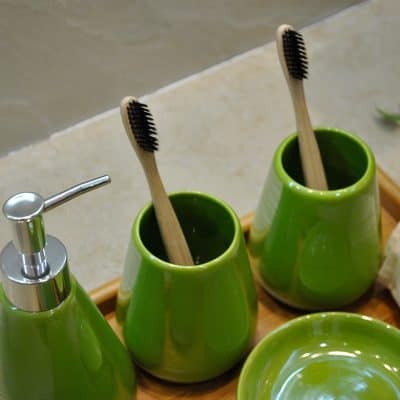 Bright green toothbrush holders with wooden toothbrushes, soap dispenser, and matching dish, modern bathroom accessories emphasizing hygiene and style, perfect for skincare and dental health at Monalisa Store.