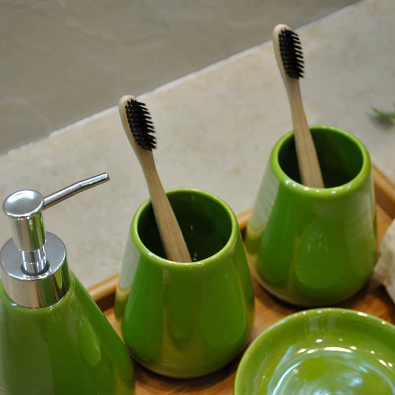 Bright green toothbrush holders with wooden toothbrushes, soap dispenser, and matching dish, modern bathroom accessories emphasizing hygiene and style, perfect for skincare and dental health at Monalisa Store.