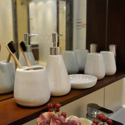 Toothbrush and liquid soap dispenser set with cups and bowls on wooden shelf as bathroom accessories at Monalisa Store in Dubai for eye care supplies.