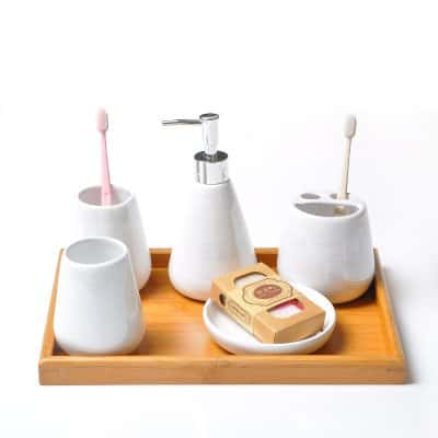 Toothbrush holder set with ceramic cups, soap dispenser, and natural soap on a wooden tray for dental hygiene.