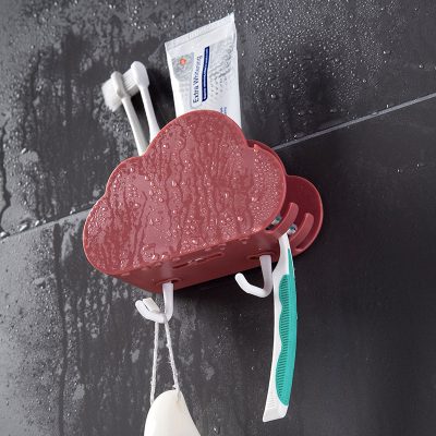 Red heart-shaped soap dish with water droplets on black tiled bathroom wall for dental care storage.