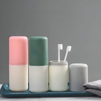Silicone toothbrush holder with two toothbrushes, reusable containers with lids, and a folded grey towel on a blue tray, showcasing modern personal care accessories at Monalisa Store.