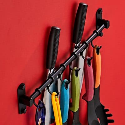 Colorful kitchen knives displayed on a wall magnetic knife strip for easy access and organization, ideal for culinary enthusiasts and professional chefs.