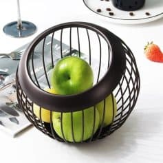 Green apples inside a modern black wire fruit basket.