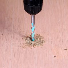 Blue and silver drill bit drilling into wood, wood shavings, woodworking tools, craft or carpentry work, Monalisa Store opt.