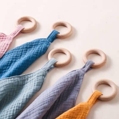 Blue and gray baby comforter with wooden rings for sensory play.