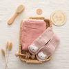 Soft pink baby socks with cat face design, eco-friendly cloth, and bamboo brush, perfect for newborns. Elegant woven basket and decorative wooden accessories create a cozy, stylish atmosphere.