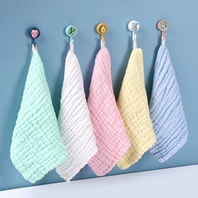 Soft pastel-colored baby towels hanging on colorful hooks at Monalisa Store, nursery essentials, plush and textured baby bath towels, gentle and absorbent baby care products for newborns and infants.