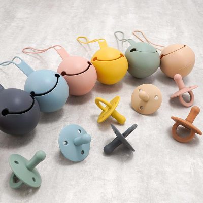 Colorful baby pacifiers and teethers in pastel shades, perfect for infants, arranged on a light surface, emphasizing safe and stylish baby accessories.