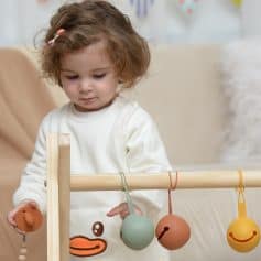 Baby girl playing with educational hanging balls at Monalisa Store, promoting children's vision development and eye health products.