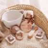 Soft baby care items displayed on cozy woven basket, including plush teddy teething toy, knitted storage, and gentle brushes, perfect for newborn and infant skincare routines.